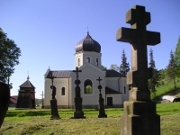 Stary cmentarz łemkowski na tle cerkwi.